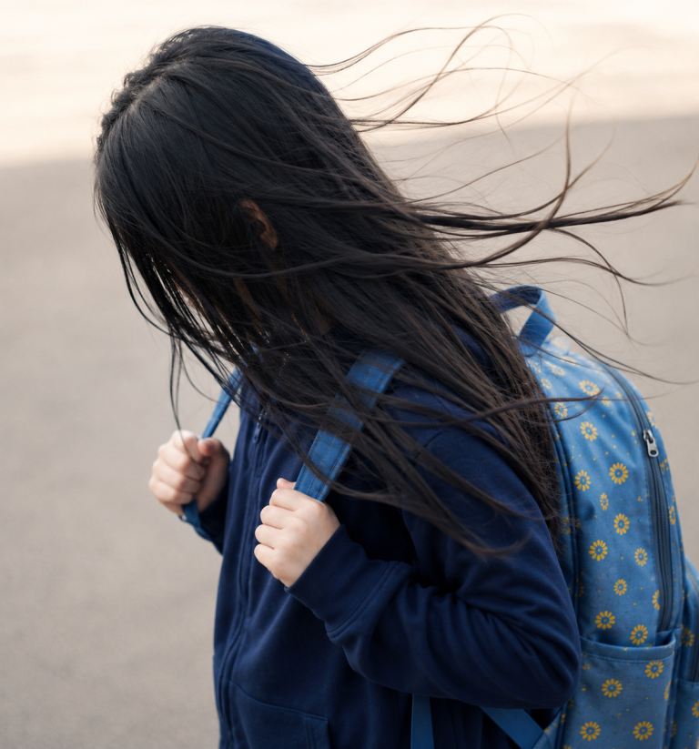 Afgesloten, buitengesloten, eenzaam op zoek naar levenspad Kind met een blauwe rugzak, haar waait in de wind terwijl het naar beneden kijkt op het strand. Psychische uitdagingen, gepest worden, slaap
